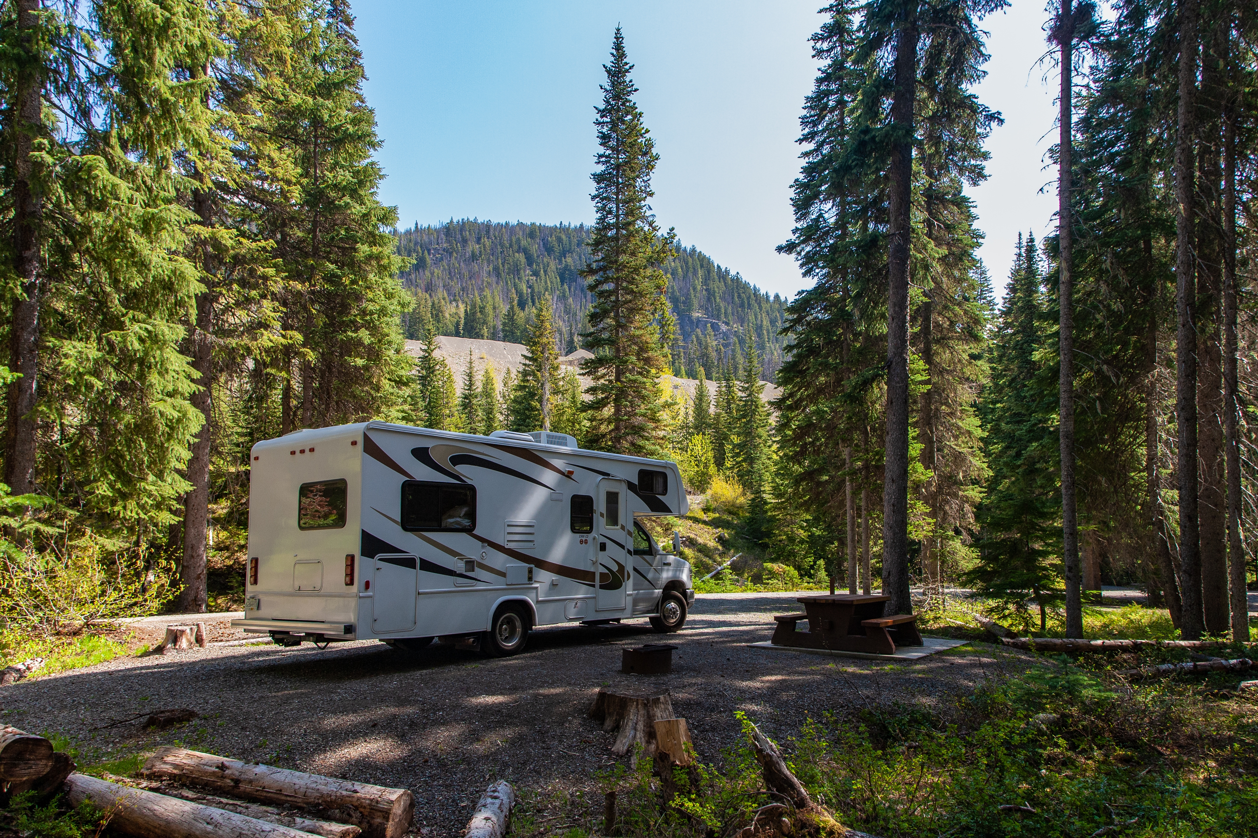 beautiful-campsite-mountains-with-rv-wooden-bench.jpg